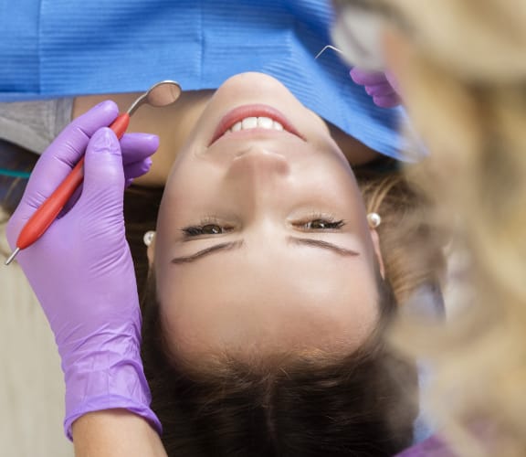 Woman laying back in detal chair getting her teeth checked out