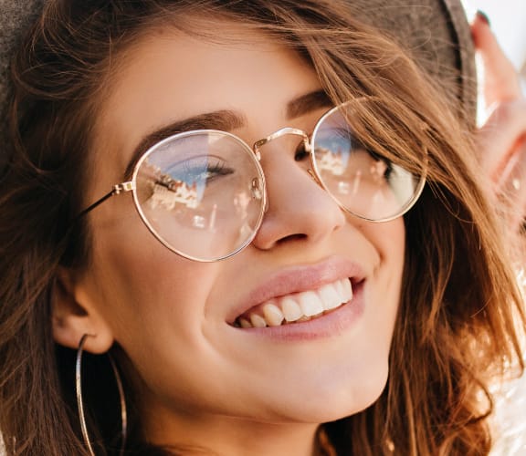 Woman wearing sun glasses and nice hat looking back over her shoulder