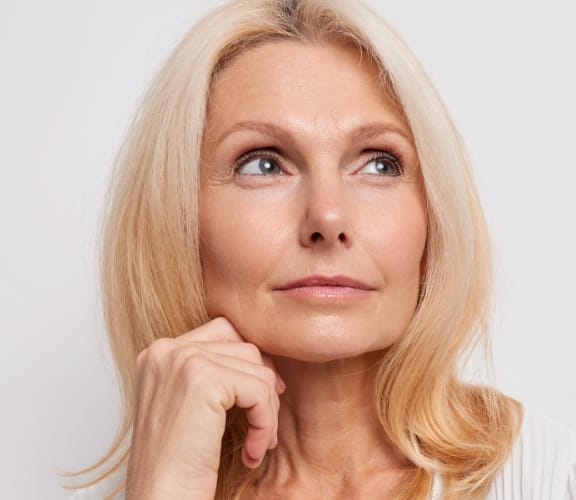 Mature woman with her fist under her chin thinking